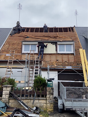 En plein travaux : Enlève les anciennes tuiles et commence à enlever l’ancien pare pluie Chantier de rénovation de toiture avec artisans couvreurs et échafaudages.